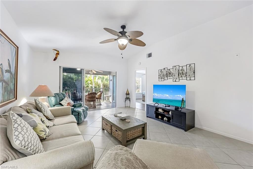 Living room featuring a ceiling fan, light tile patterned floors, and vaulted ceiling