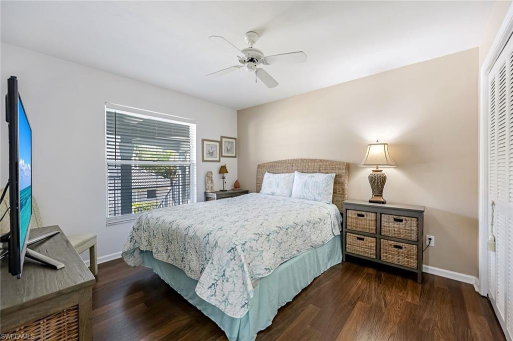 Bedroom with dark wood-style flooring, ceiling fan, and a closet