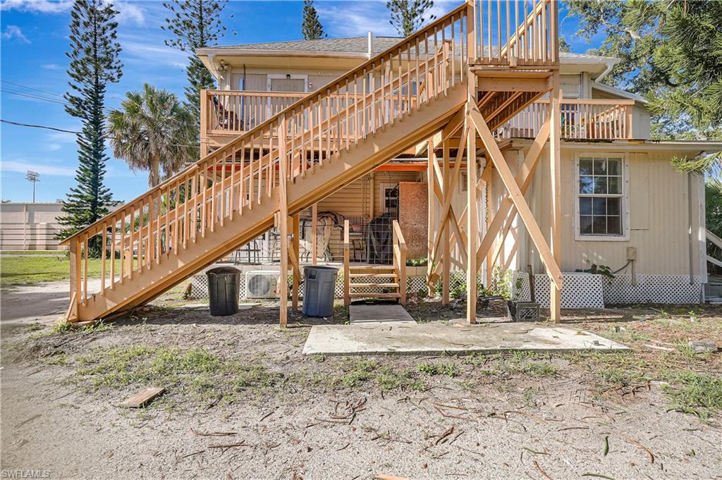 Back of property featuring stairway, a deck, and a patio area