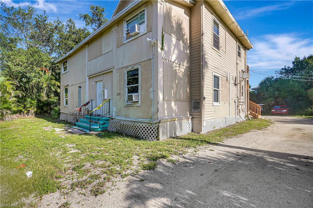 Rear view of house with entry steps and a lawn