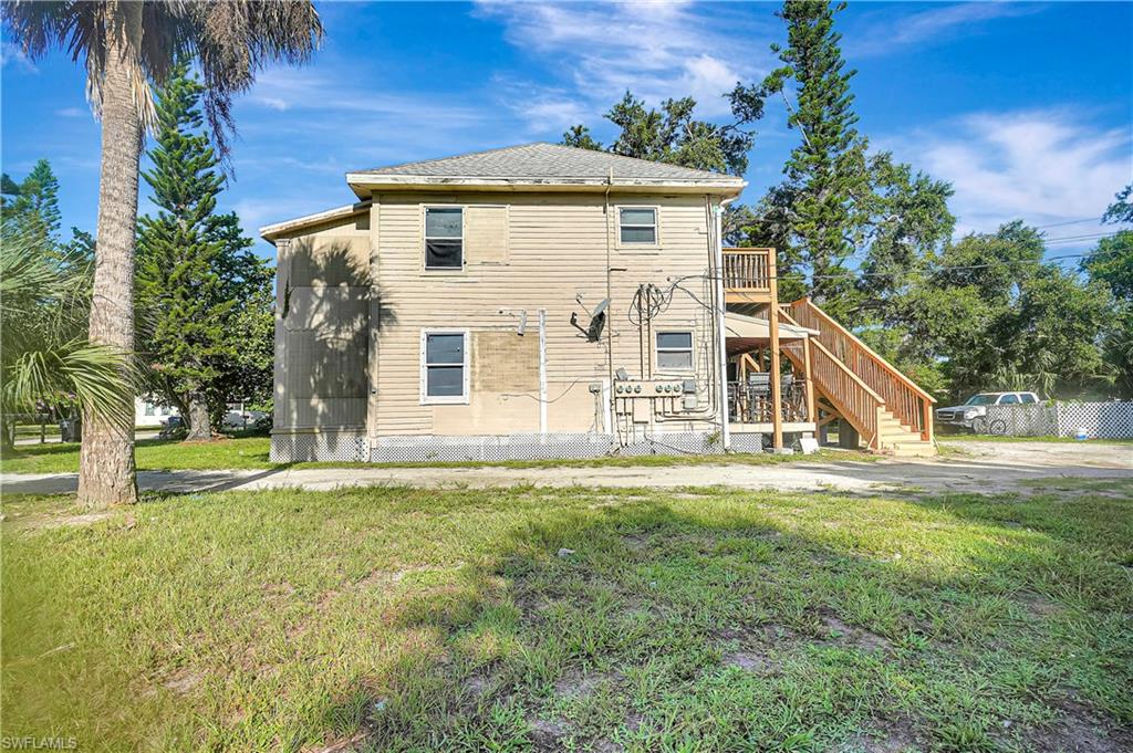 Rear view of house featuring a deck, stairway, and a yard