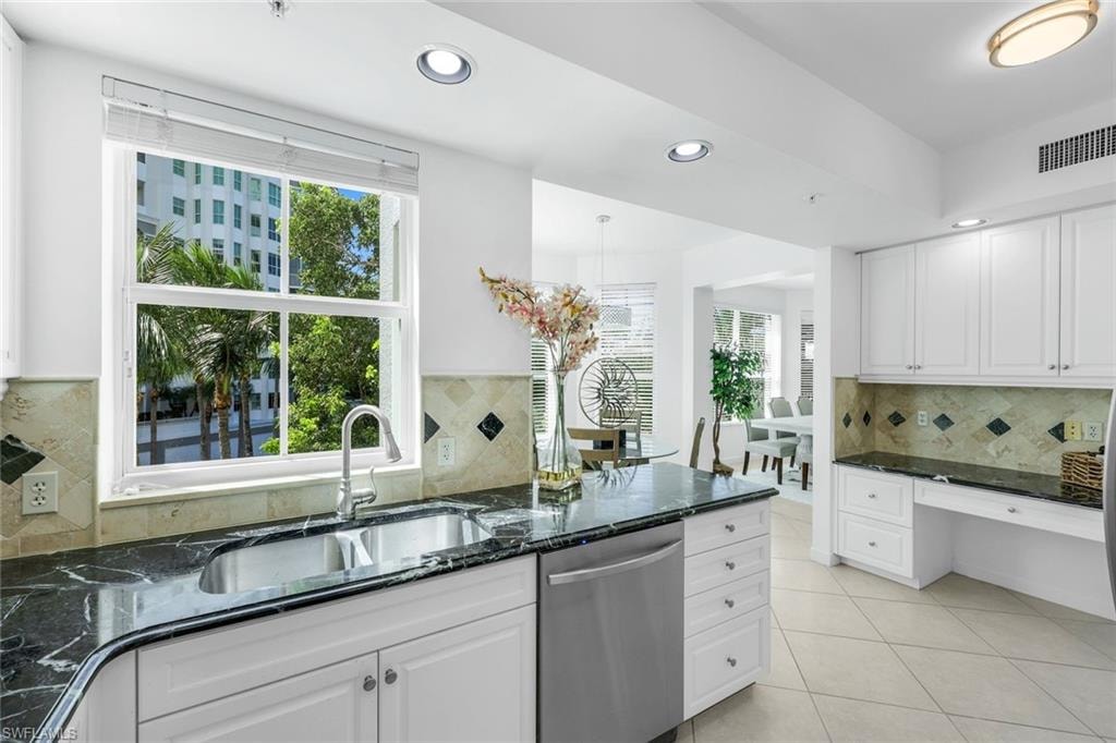 Kitchen featuring dark stone counters, backsplash, recessed lighting, dishwasher, and white cabinetry