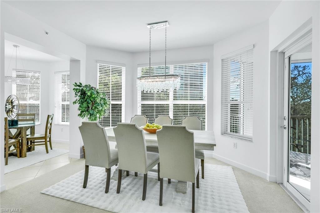 Dining space with a chandelier, light colored carpet, and light tile patterned floors