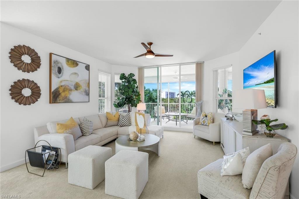 Carpeted living area featuring a ceiling fan and floor to ceiling windows