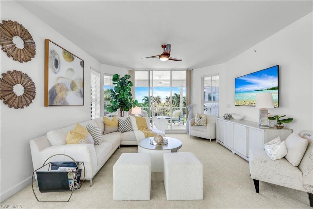 Carpeted living area with a ceiling fan and floor to ceiling windows