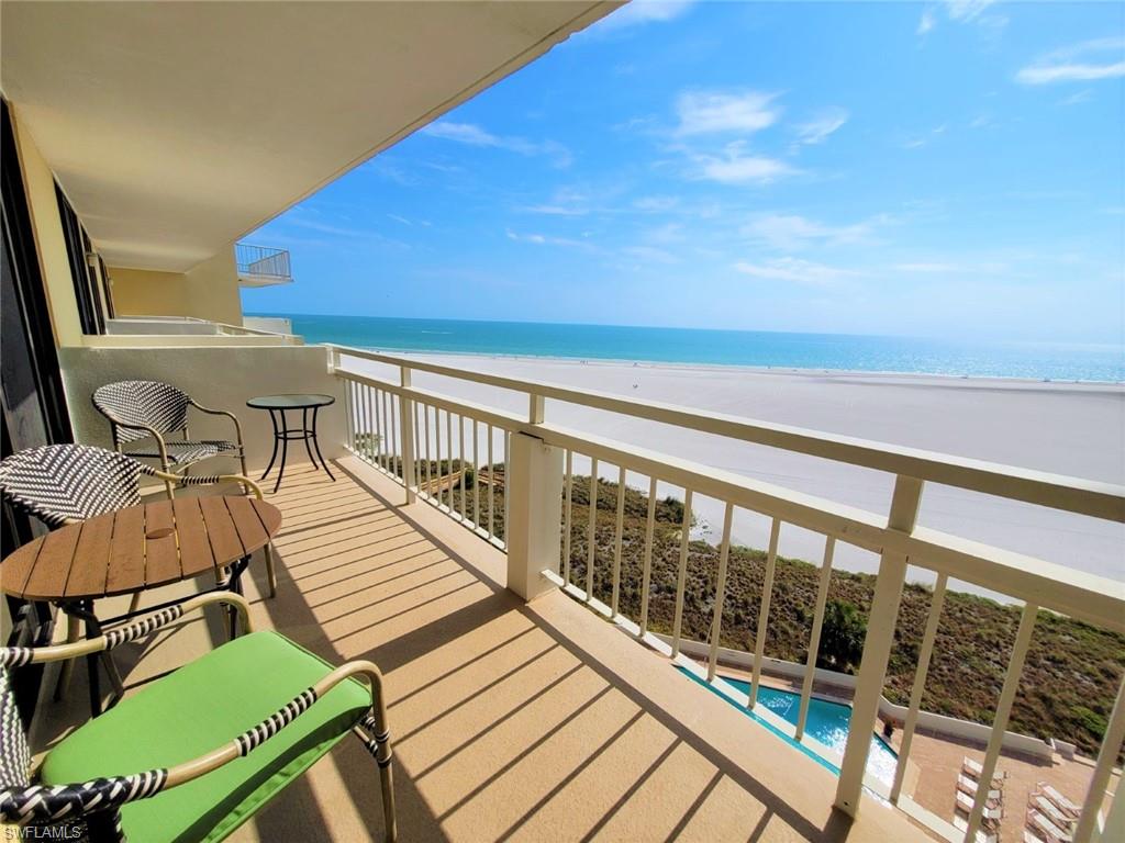 Balcony with view of water and beach and view of pool area