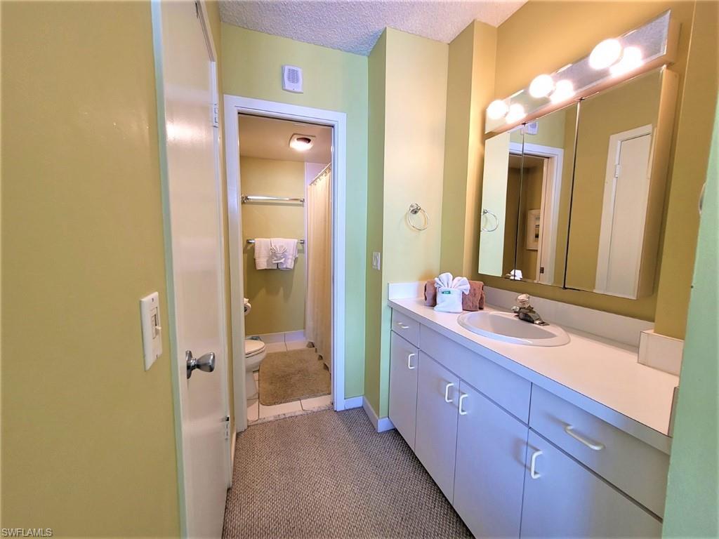 Bathroom with vanity, dark tile patterned floors, a textured ceiling, and curtained shower