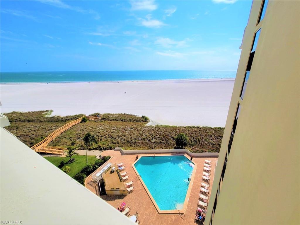 Community pool featuring view of water and beach and a patio area