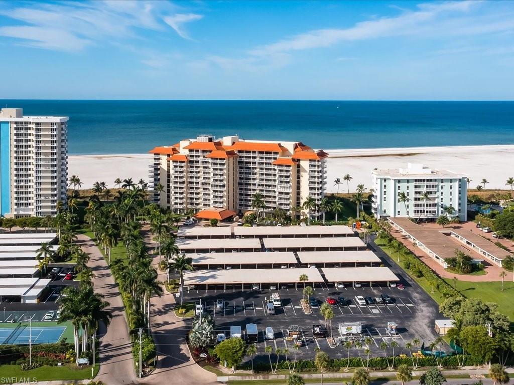 Bird's eye view of apartment complex and waterfront with a beach