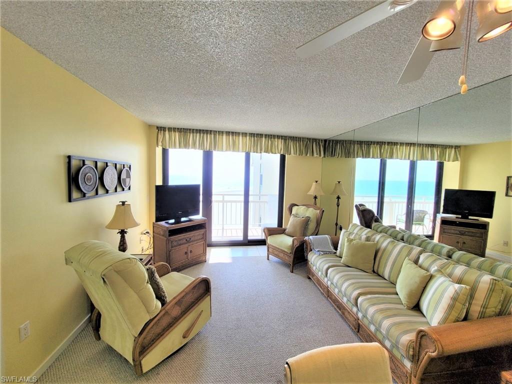 Living area featuring a textured ceiling, carpet floors, healthy amount of natural light, and ceiling fan