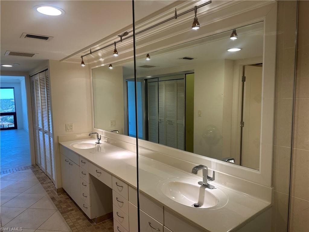 Full bath featuring a closet, double vanity, light tile patterned floors, recessed lighting, and track lighting