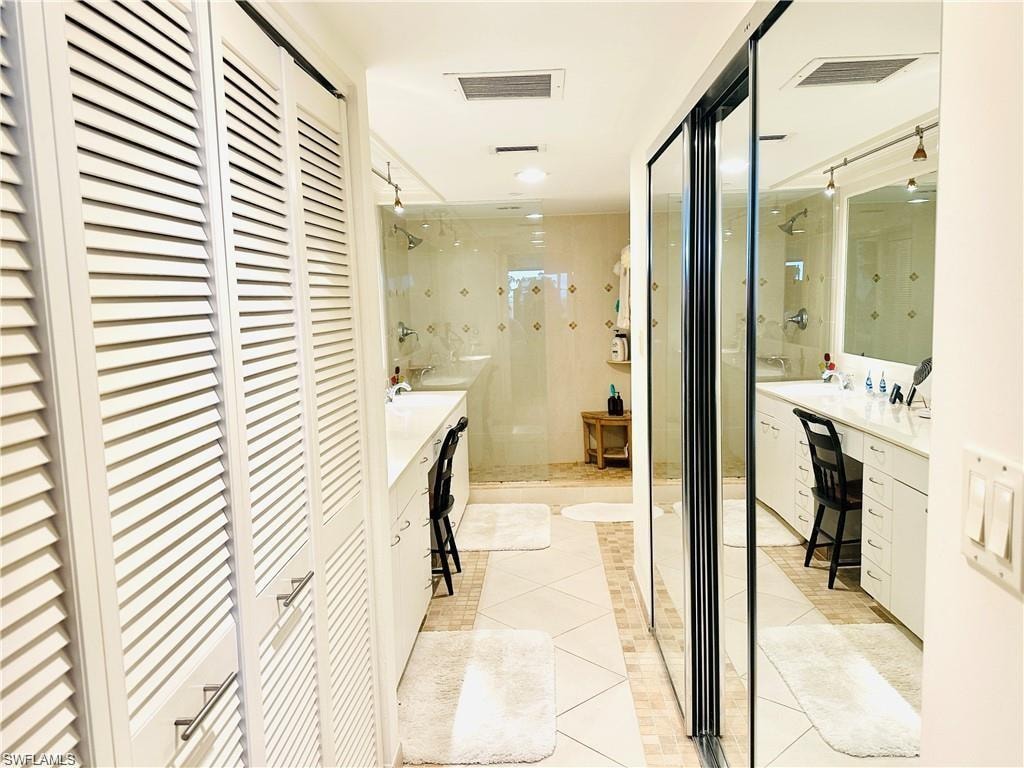 Bathroom featuring a closet, vanity, a shower stall, and light tile patterned flooring