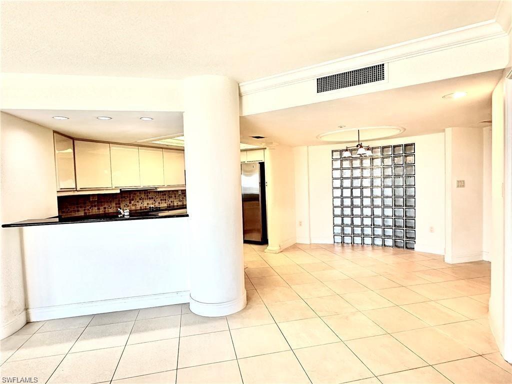 Kitchen featuring backsplash, light tile patterned floors, freestanding refrigerator, recessed lighting, and dark countertops
