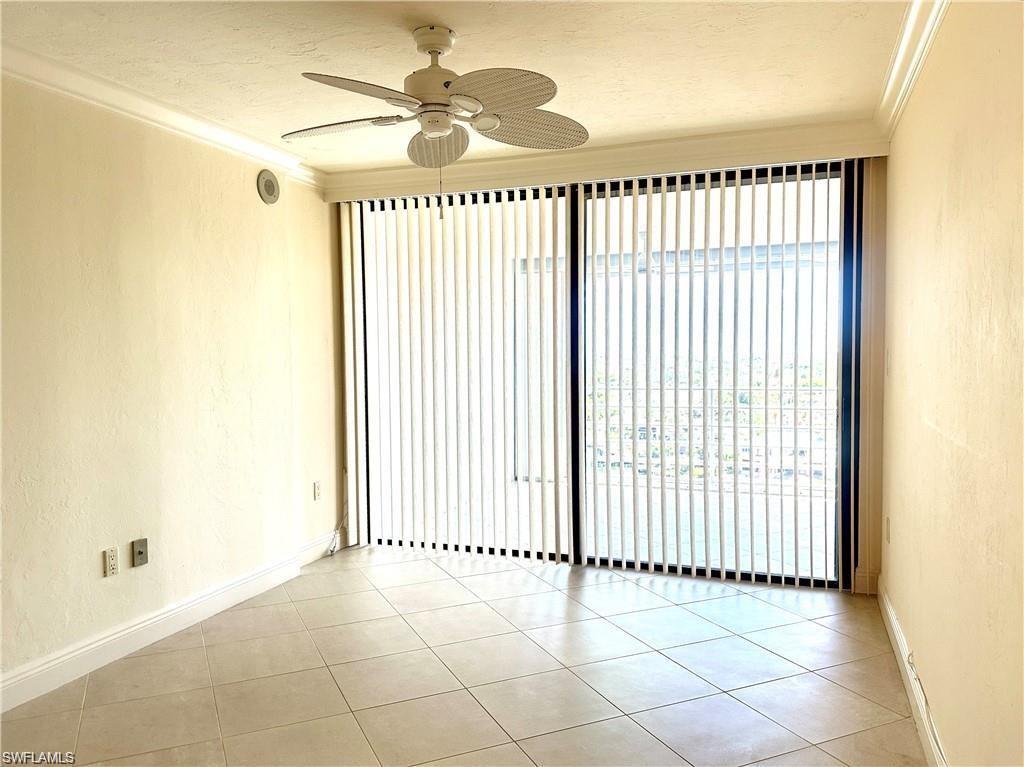Spare room with a textured wall, ornamental molding, ceiling fan, light tile patterned floors, and a textured ceiling