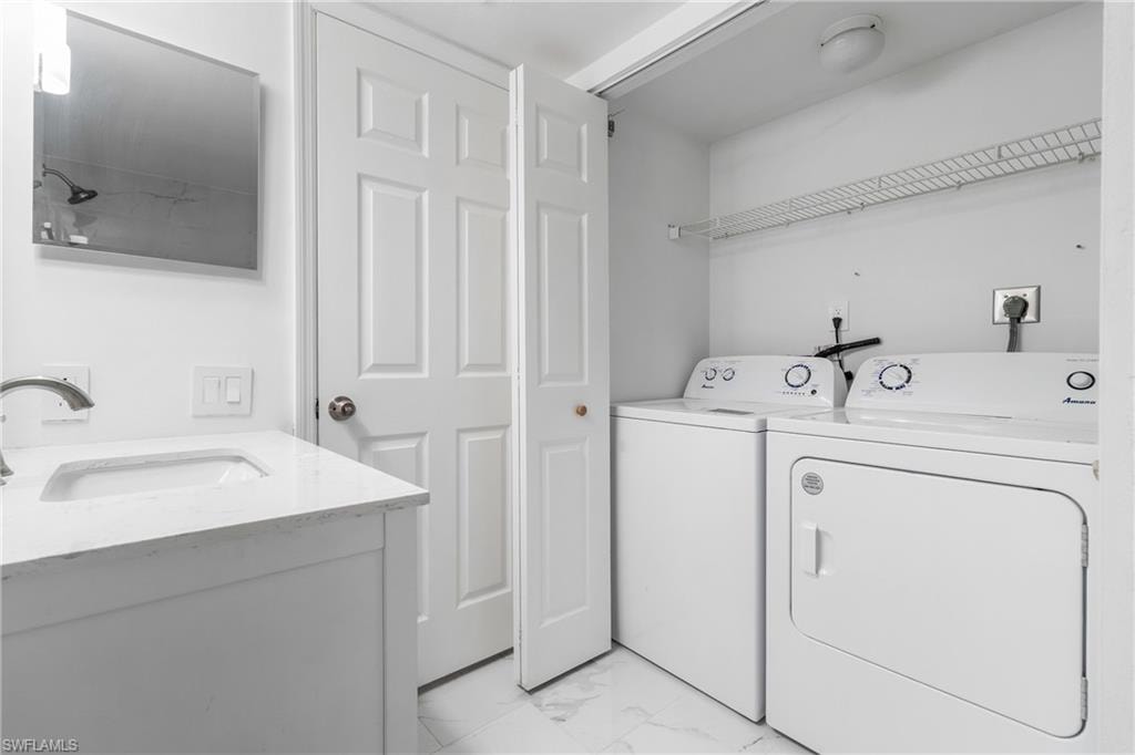 Washroom featuring light marble finish floors and washing machine and dryer