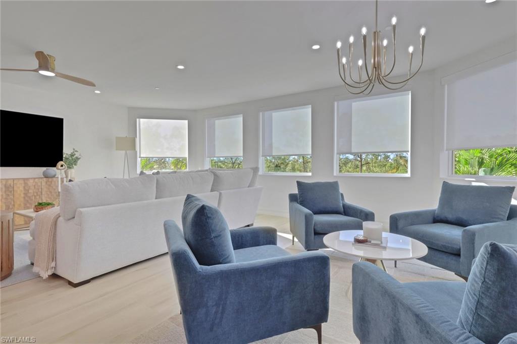 Living area featuring wood finished floors, healthy amount of natural light, recessed lighting, and a chandelier
