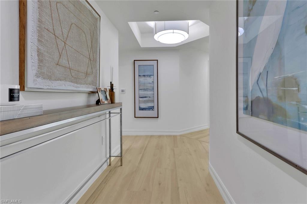 Hall with light wood-type flooring and a tray ceiling