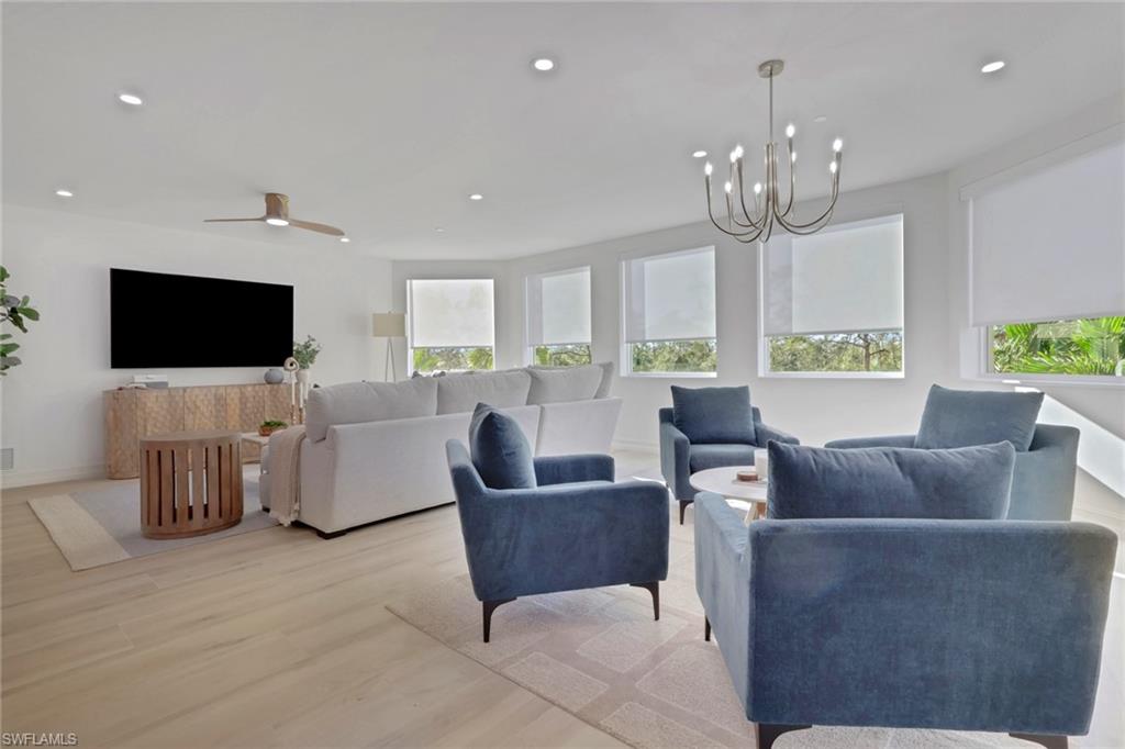 Living room featuring wood finished floors, recessed lighting, ceiling fan, and a chandelier