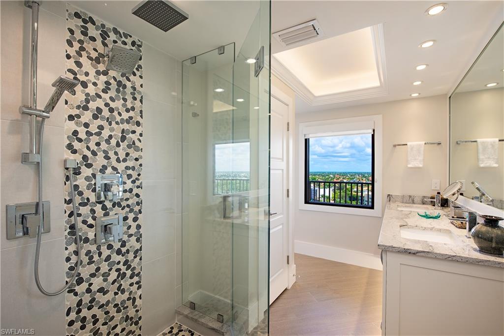 Full bathroom featuring a deluxe shower stall, a raised ceiling, double vanity, wood finished floors, and recessed lighting