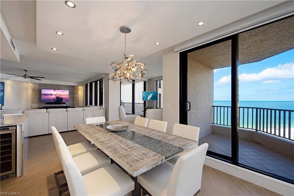 Dining area featuring light wood finished floors, a water view, recessed lighting, a chandelier, and wine cooler