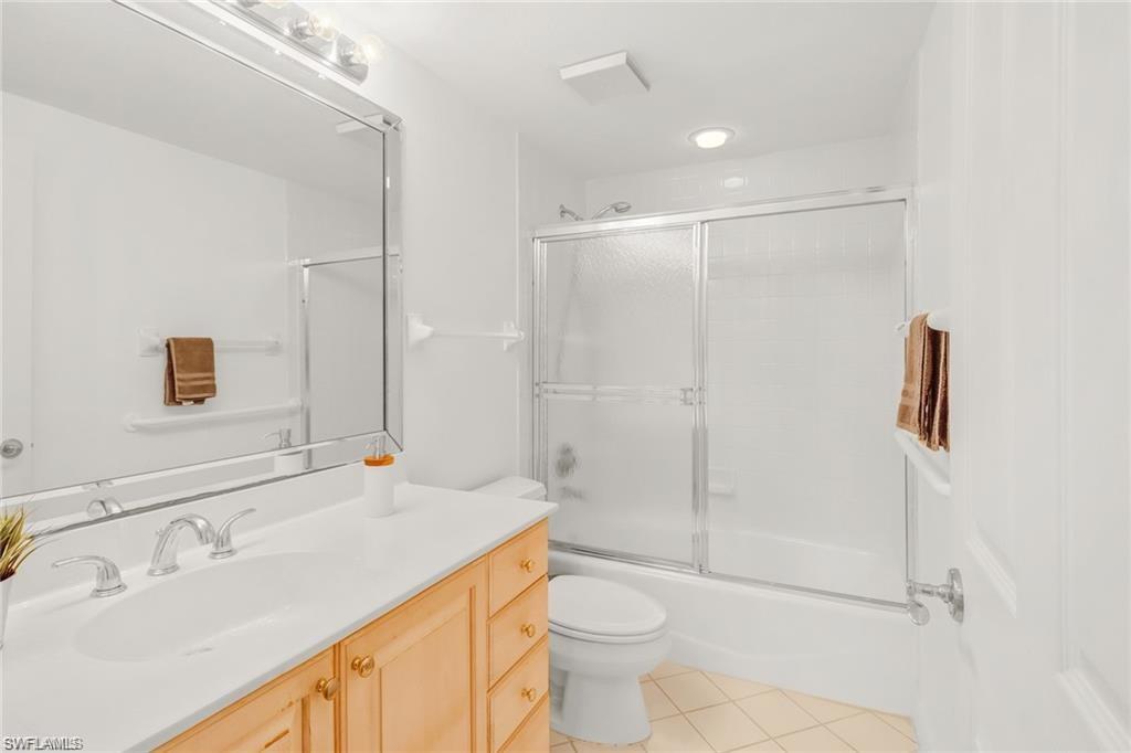 Bathroom featuring bath / shower combo with glass door, vanity, and light tile patterned floors