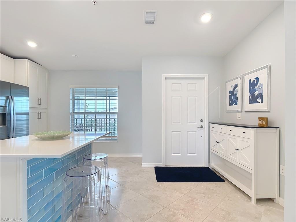 Entryway with light tile patterned flooring and recessed lighting