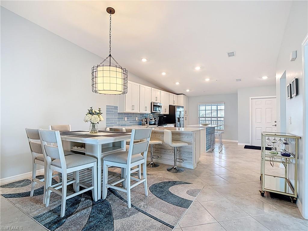 Dining room featuring vaulted ceiling, light tile patterned flooring, and recessed lighting