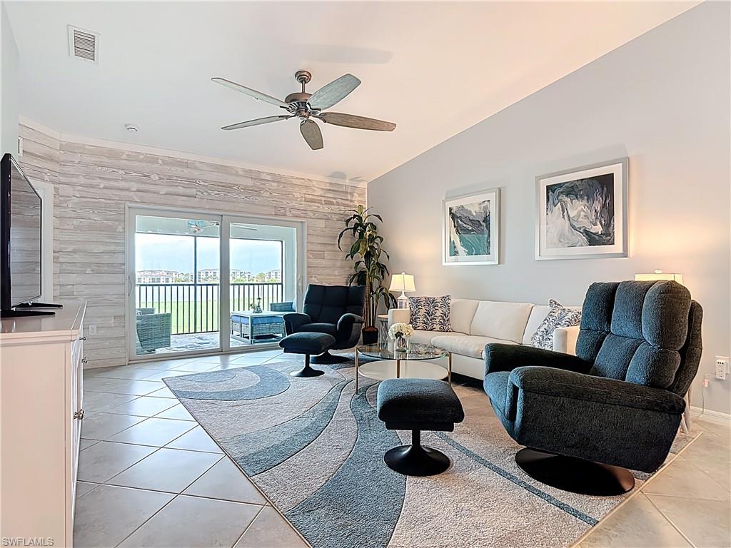 Living area featuring wood walls, light tile patterned flooring, a ceiling fan, and vaulted ceiling