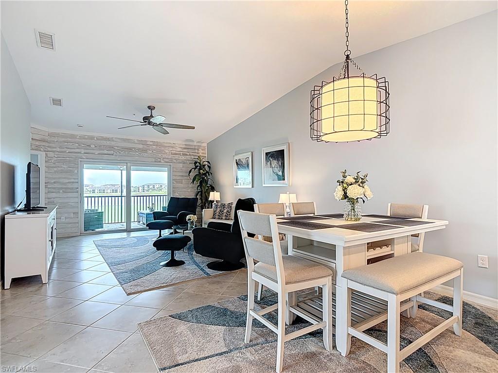Dining room with vaulted ceiling, light tile patterned flooring, and ceiling fan
