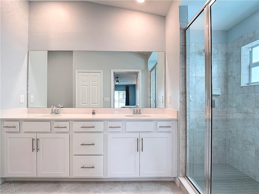 Bathroom with a shower stall, double vanity, a ceiling fan, and light tile patterned floors