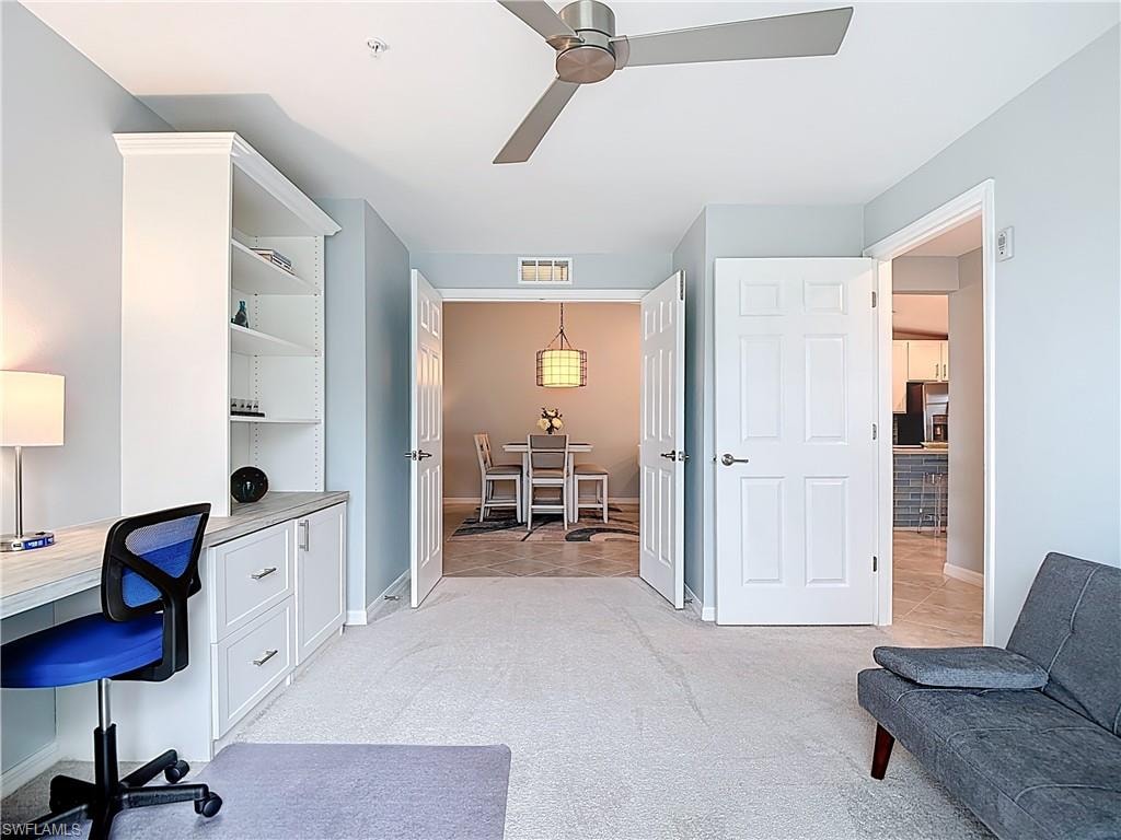 Office area with light carpet, a ceiling fan, and built in desk