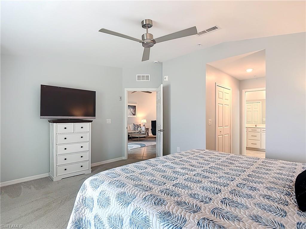 Bedroom with light carpet, ensuite bath, and a ceiling fan
