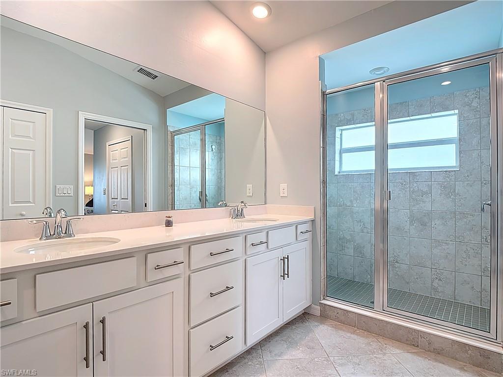 Full bathroom featuring a shower stall, double vanity, light tile patterned floors, and recessed lighting
