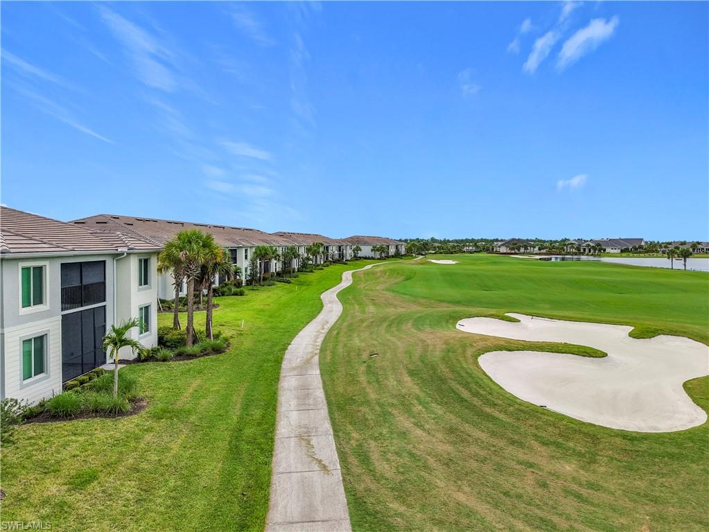 View of community with view of golf course and a yard