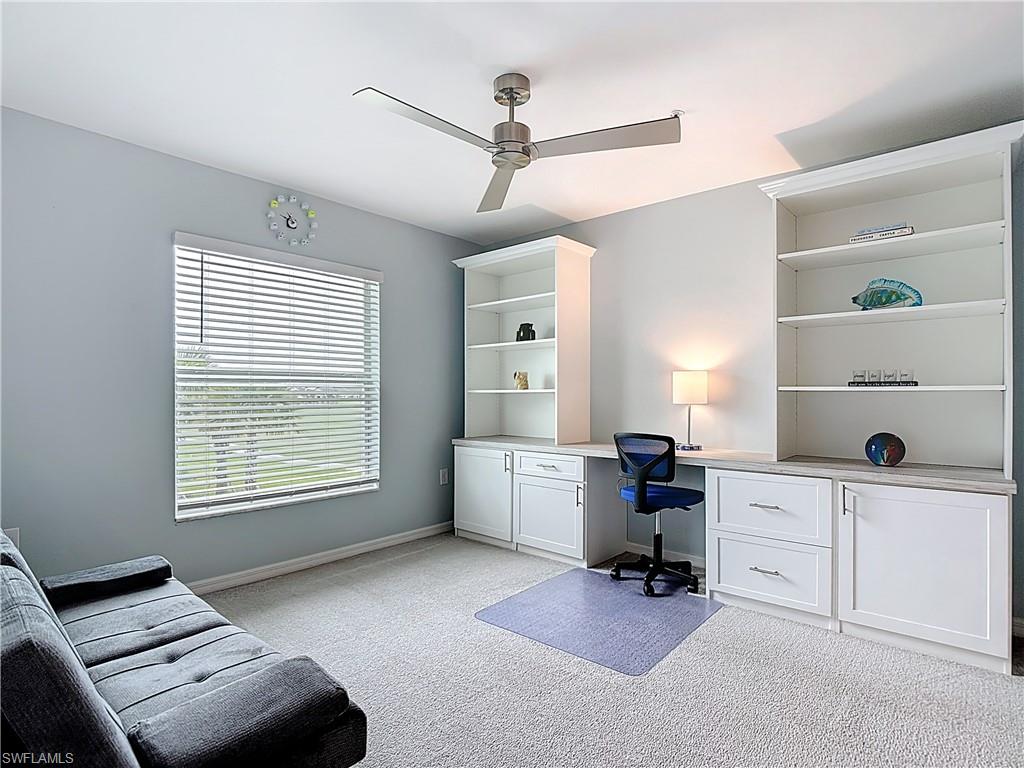 Office space featuring built in desk, light carpet, and a ceiling fan