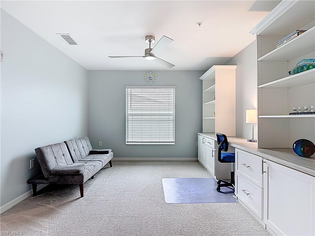 Home office featuring built in study area, light colored carpet, and ceiling fan
