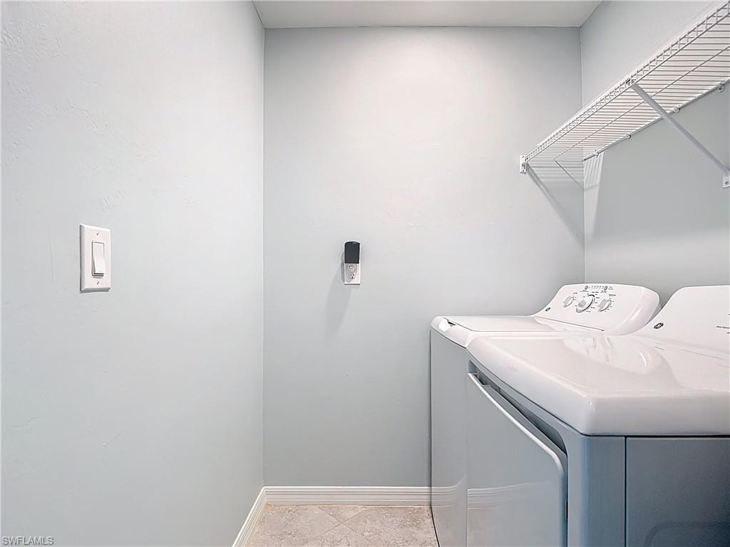 Washroom with separate washer and dryer and light tile patterned floors