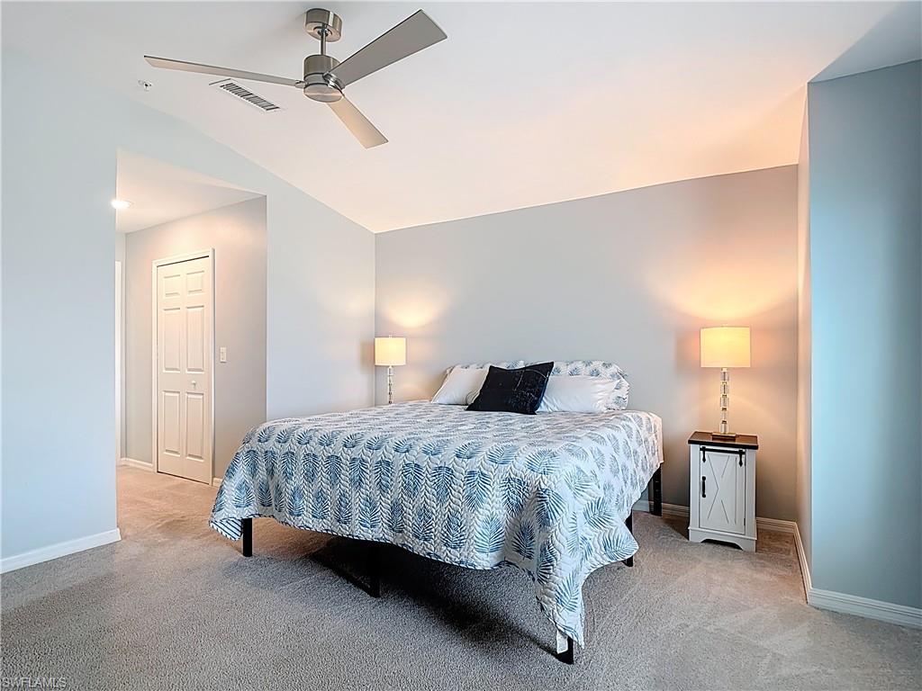 Bedroom with light carpet, ceiling fan, and lofted ceiling
