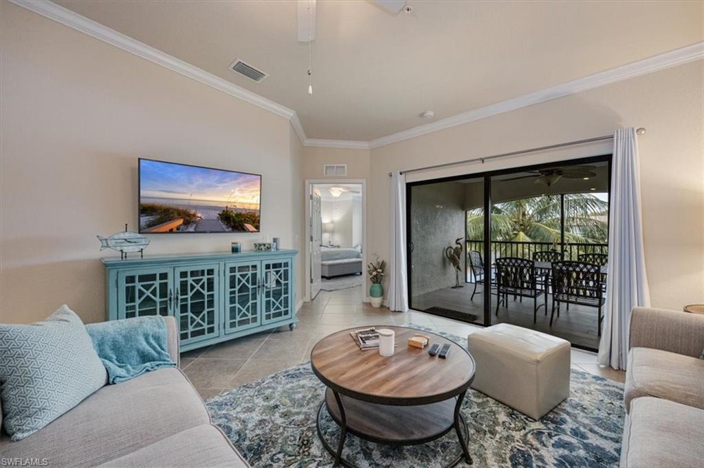 Tiled living room with vaulted ceiling, ceiling fan, and crown molding