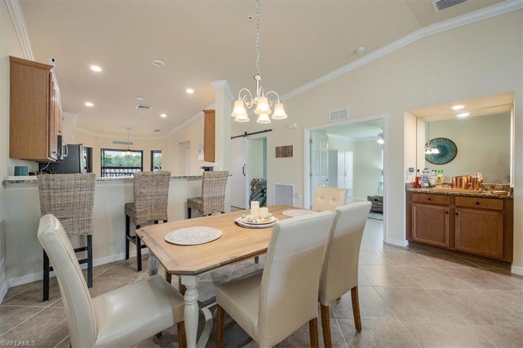 Dining space featuring crown molding, light tile patterned flooring, and a barn door