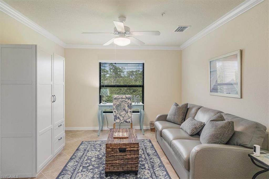 Living room with ceiling fan, crown molding, and light tile patterned floors