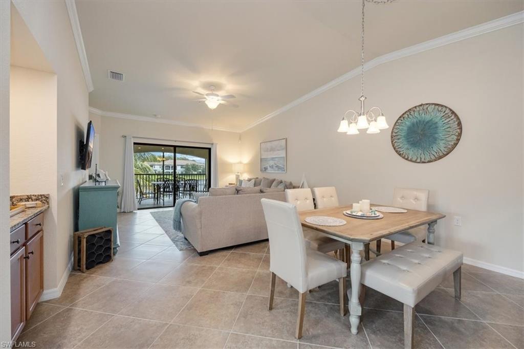 Dining room with crown molding, light tile patterned flooring, and a notable chandelier