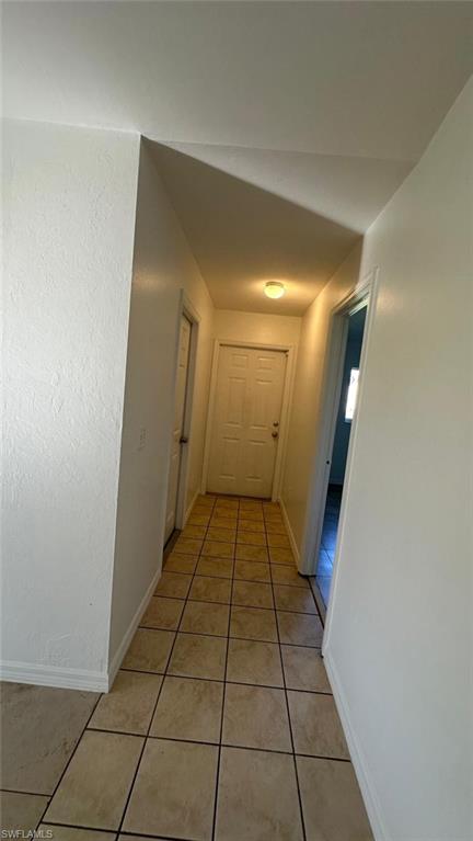 Hallway featuring light tile patterned floors and baseboards