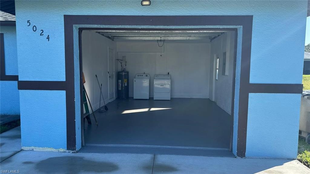Garage featuring water heater and washer and clothes dryer