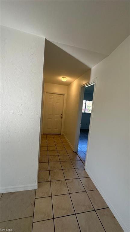 Hall featuring light tile patterned flooring and baseboards
