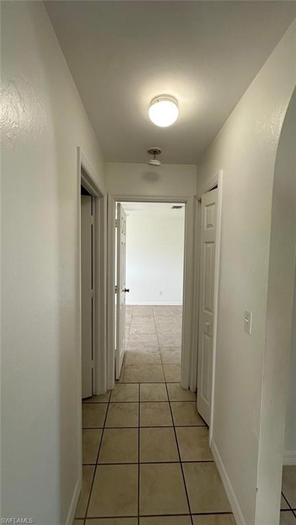 Corridor featuring light tile patterned floors and arched walkways