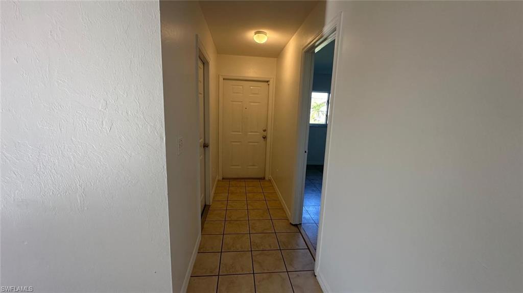 Hallway featuring light tile patterned floors and baseboards