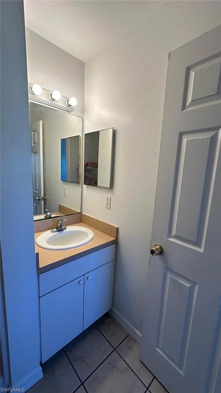 Bathroom featuring vanity, light tile patterned floors, and a textured wall