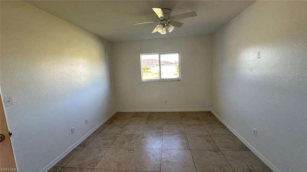 Empty room featuring light tile patterned flooring and a ceiling fan