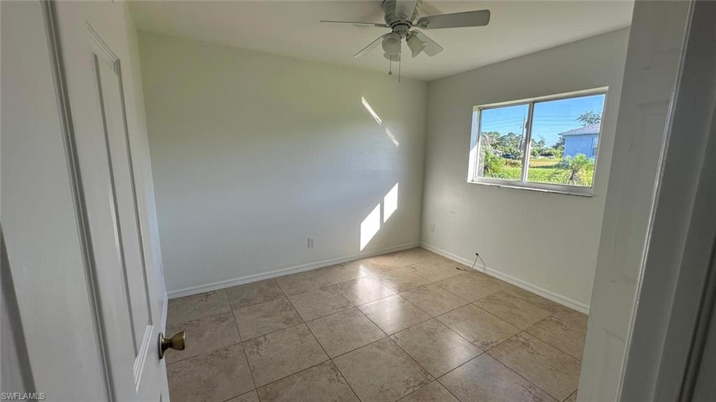 Unfurnished room with ceiling fan and light tile patterned floors